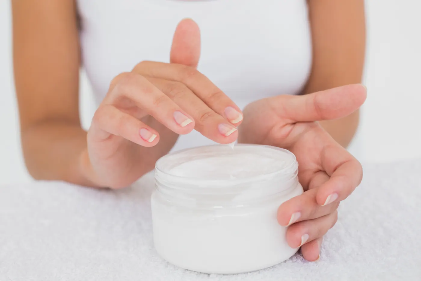 Mãos abrindo um pote de creme corporal